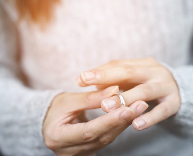 woman feeling stressed and angry, and relationships problems couple. single sad wife after divorce lamenting holding the wedding ring marry. Frau probiert einen Ring an